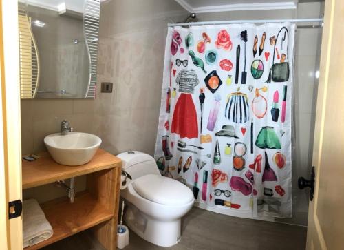 La salle de bains est pourvue de toilettes et d'un rideau de douche avec des chaussures. dans l'établissement mirabosque new aparments 2, à Osorno