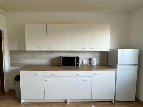 a white kitchen with a microwave and a refrigerator at Zimmer 1 in Bullendorf