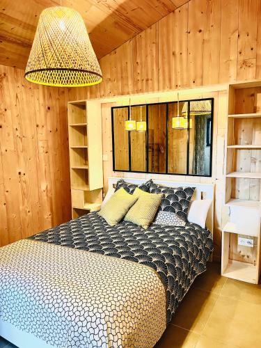une chambre avec un lit dans une pièce aux murs en bois dans l'établissement La cabane 56 - calme - cosy - confortable - sois les chênes - sans vis-à-vis, à Lège-Cap-Ferret