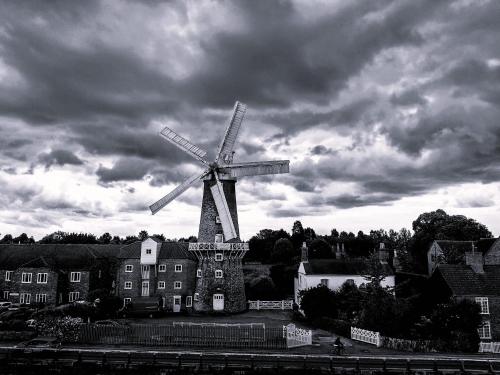 a windmill in front of a building with a cloudy sky at The King's Arms in Boston