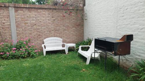two white chairs and a piano in a yard at Departamento a 100mts de los Portones del Parque in Mendoza