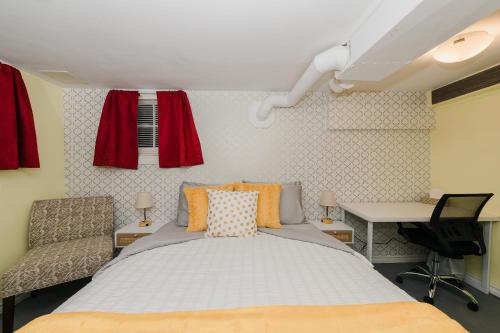 Quaint & Cozy Accommodation في إيدمونتون: غرفة نوم بسرير ومكتب وستائر حمراء