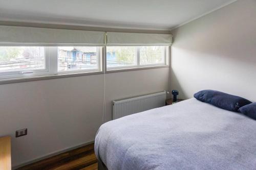 a bedroom with a bed and two windows at Estilo Valdiviano, depto2D/1B in Valdivia