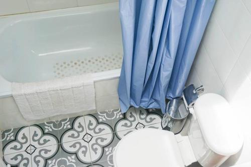 a bathroom with a toilet and a blue curtain at Estilo Valdiviano, depto2D/1B in Valdivia