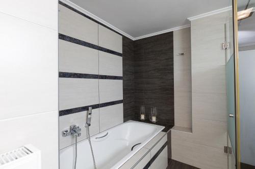 a bathtub in a bathroom with white and black tiles at Villa THAMI in Almirida