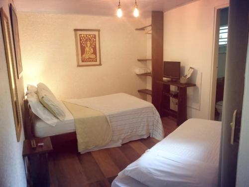 um quarto de hotel com duas camas e uma televisão em Pousada Alfa e Ômega em Alto Paraíso de Goiás