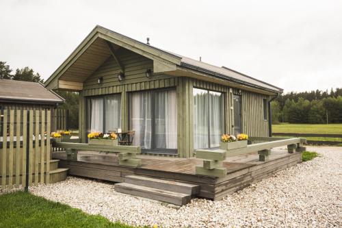 ein kleines Haus mit einer Terrasse mit Blumen darauf in der Unterkunft Green Valley vacation homes in Žocenes Ciems