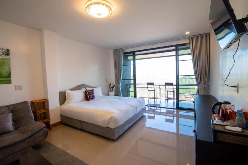 1 dormitorio con cama, sofá y balcón en Oasis Phamee en Ban Pha Mi