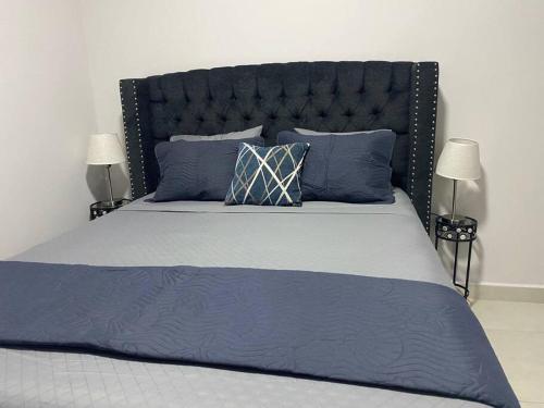 a large bed with a black headboard and blue pillows at Céntrico Apartamento in Santa Rosa de Copán