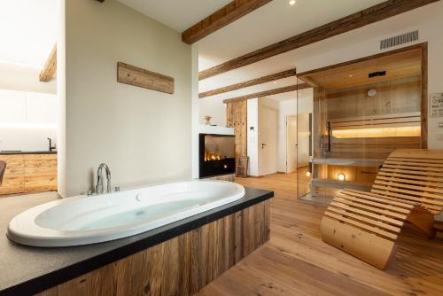 Erbacher Living Nature Apartments Suites في بولسانو: حمام كبير مع حوض استحمام ودش زجاجي