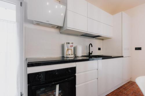 a kitchen with white cabinets and a black appliance at Pinzolo Ski Lodge Retreat in Pinzolo