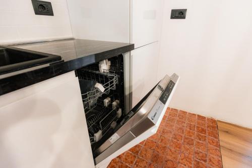 an empty dishwasher in a kitchen with a tile floor at Pinzolo Ski Lodge Retreat in Pinzolo