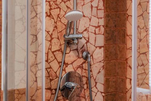 a shower in a bathroom with a stone wall at Pinzolo Ski Lodge Retreat in Pinzolo