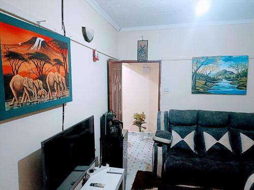 ein Wohnzimmer mit einem Sofa und einem TV in der Unterkunft @princess Dee in Meru
