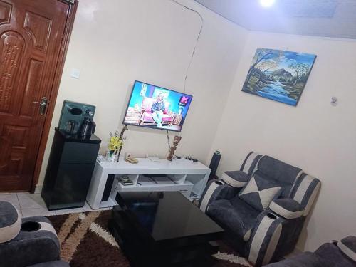 ein Wohnzimmer mit 2 Stühlen und einem TV an der Wand in der Unterkunft @princess Dee in Meru