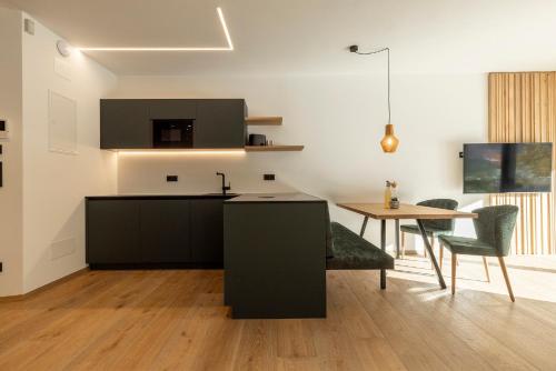 Erbacher Living Nature Apartments Suites في بولسانو: مطبخ مع طاولة وغرفة طعام