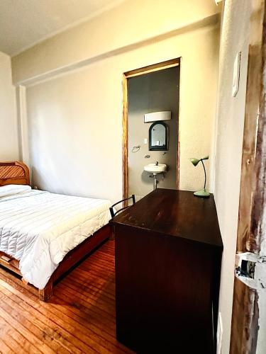 a bedroom with a bed and a dresser and a mirror at FRONTERA 49 Roma Norte Hostal in Mexico City
