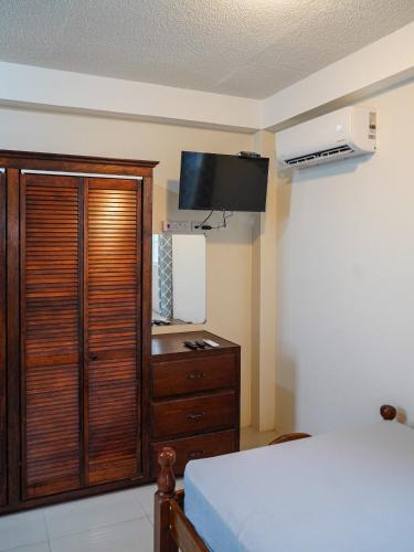 a bedroom with a bed and a dresser with a television at City Comfort in Roseau