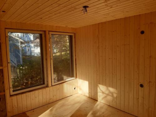 um quarto vazio com duas janelas e um piso de madeira em Garden Chamber em Rovaniemi