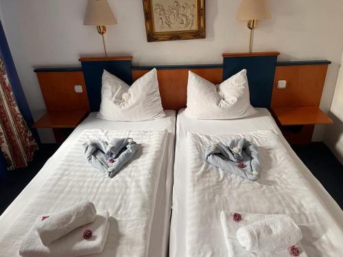 two beds with towels in the shape of hands on them at Hotel zur Brücke in Herzogenrath