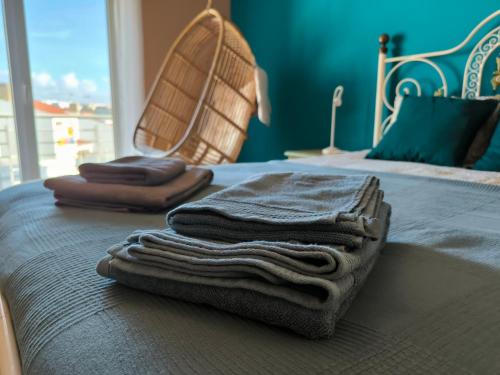 une pile de serviettes assises au-dessus d'un lit dans l'établissement Ericeira Seaside Escape, à Ericeira