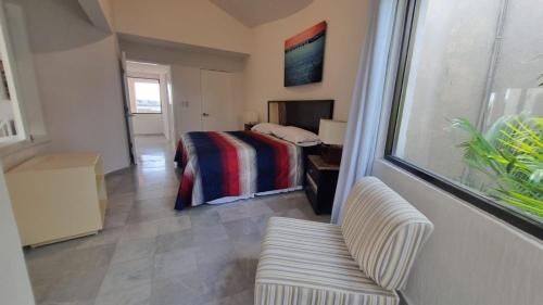 a bedroom with a bed and a couch and a window at Villas La Marina in Cancún