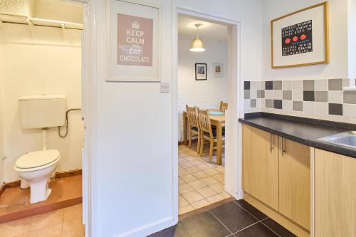 a bathroom with a toilet and a kitchen with a table at Host & Stay - Prospect Place in Canterbury