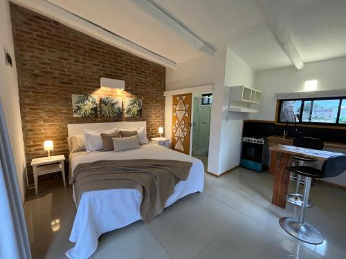 1 dormitorio con 1 cama grande y pared de ladrillo en Cabin studio Cerca del mar - José Ignacio, en José Ignacio