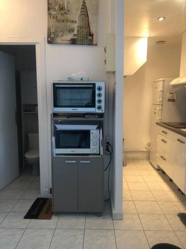 uma cozinha com um micro-ondas num armário com um fogão em Croisette Immo Cosy 2p derrière le Martinez em Cannes