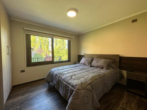 um quarto com uma cama e uma grande janela em Mirabosque aparment Ejecutivos 6 em Osorno