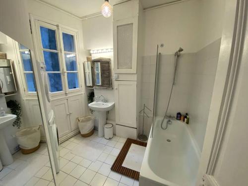 a white bathroom with a tub and a sink at Le Cœur de l’Île Saint-Louis, you will love it! in Paris