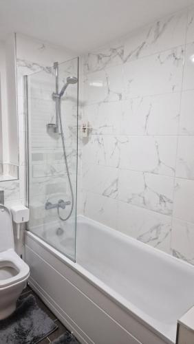 a white bathroom with a shower and a toilet at London City Apartment One in Ealing