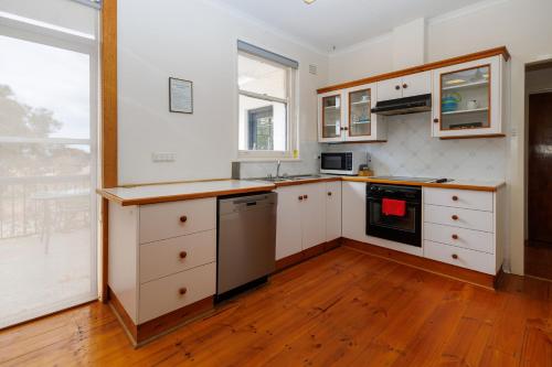 a kitchen with white cabinets and a wooden floor at BIG4 Cape Jervis Accommodation & Caravan Park in Cape Jervis