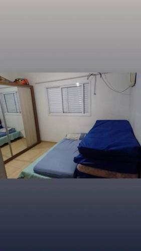 - une chambre avec un lit doté de draps bleus et une fenêtre dans l'établissement Casa com piscina perto da praia, à Caraguatatuba