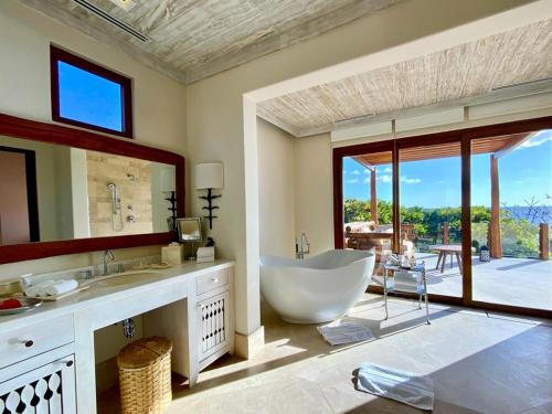 a bathroom with a large tub and a large window at Mukul Resort in Tola