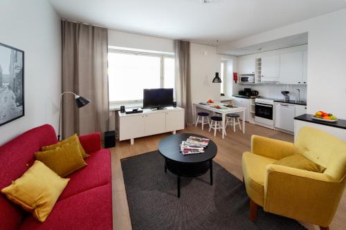 a living room with a red couch and yellow chairs at Forenom Serviced Apartments Helsinki Kruununhaka in Helsinki