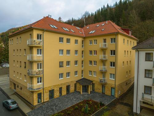 a large yellow building with a red roof at Miner's Lodge in Jáchymov