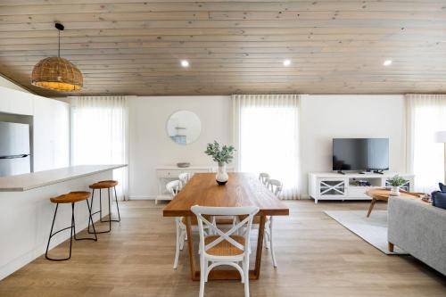 a kitchen and living room with a wooden ceiling at Kaia's Beach Retreat in Mollymook