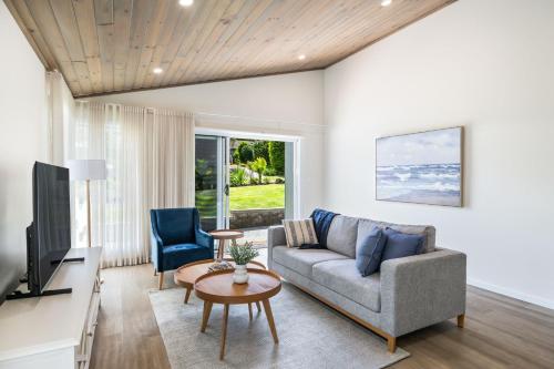 a living room with a couch and a tv at Kaia's Beach Retreat in Mollymook