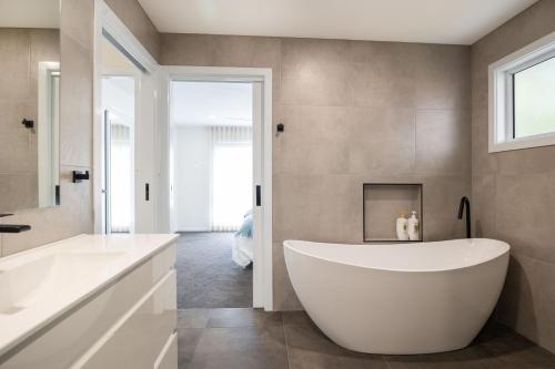 a large white tub in a bathroom with a window at Kaia's Beach Retreat in Mollymook