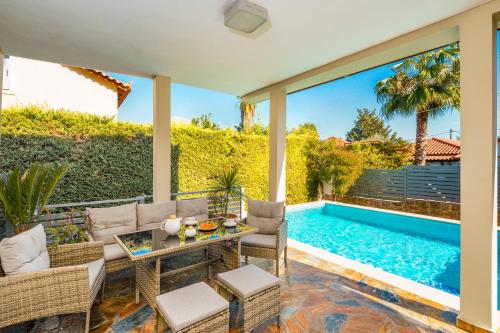 a patio with a table and chairs next to a swimming pool at Athina Sea Villa Close To Athens in Oropós