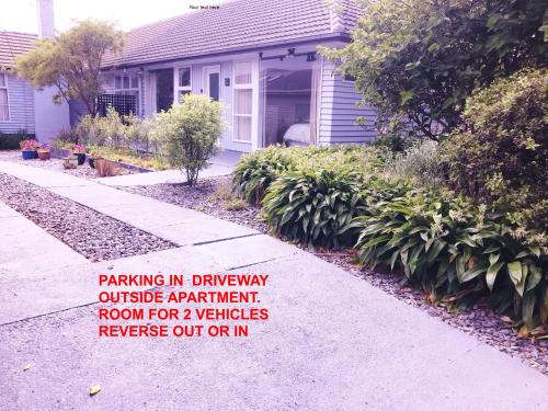 Pukerua Bay的住宿－Peaceful Pukerua Bay，带有标志的房子,上面写着车道上停车的标志,位于公寓房外