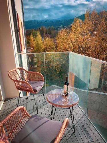 a balcony with two chairs and a table with a bottle of wine at RJ Apartament widok na Śnieżkę in Karpacz