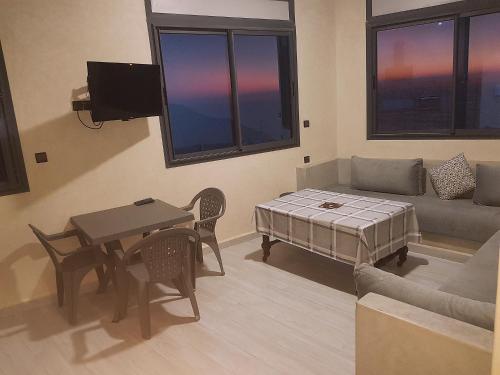 een woonkamer met een bank en een tafel bij Amouage résidence in Sidi Ifni