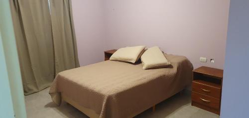 Departamentos Ariadna في كومودورو ريفادافيا: غرفة نوم عليها سرير ووسادتين