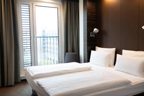 a bedroom with a large bed with a large window at Motel One Düsseldorf Hauptbahnhof in Düsseldorf