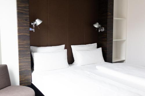 a bedroom with two beds with white pillows at Motel One Düsseldorf Hauptbahnhof in Düsseldorf