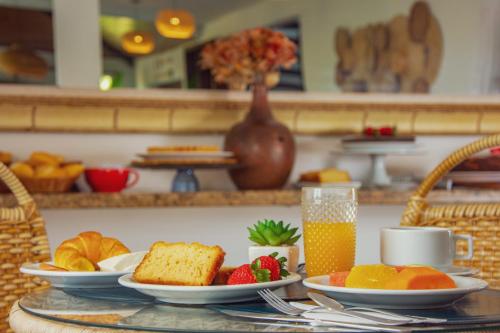 a table with plates of fruit and a glass of orange juice at Pousada MAR João Fernandes in Búzios