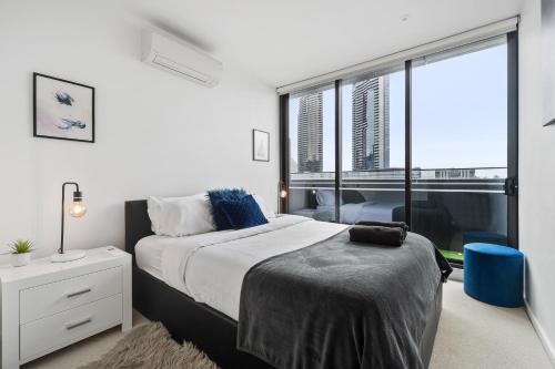 a bedroom with a bed and a large window at Melbourne Docklands Riverside Views in Melbourne