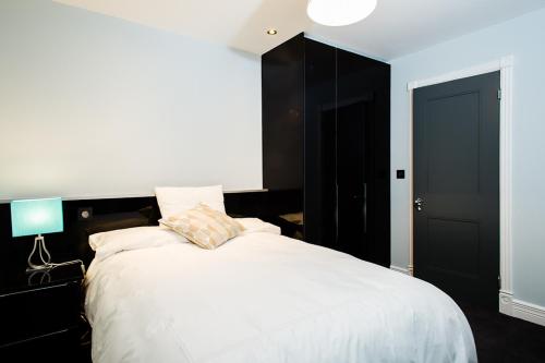 1 dormitorio con 1 cama blanca grande con lámpara azul en Luxury Townhouse, en Dublín